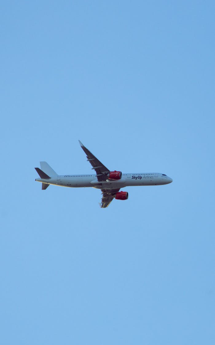 Passenger plane flying high in the clear blue sky, showcasing aviation technology.