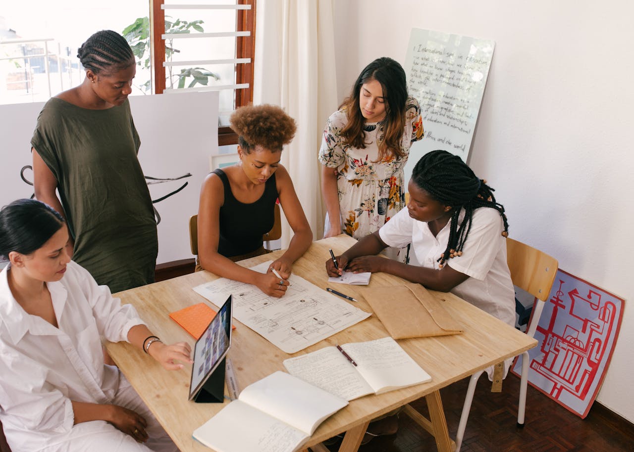 contact-bg Diverse team collaborates on a project using digital and paper resources in a bright office.