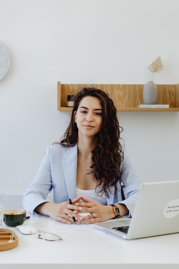 services-bg Portrait of a confident businesswoman sitting at a desk with a laptop in a modern office.