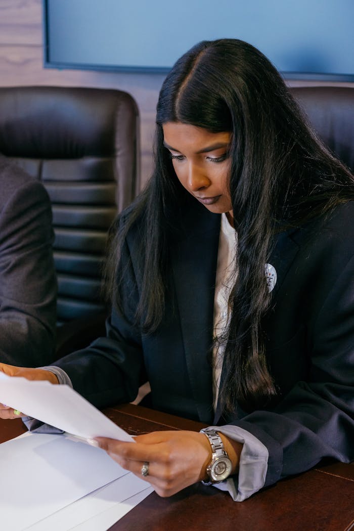 A focused professional woman reading documents at an office desk.